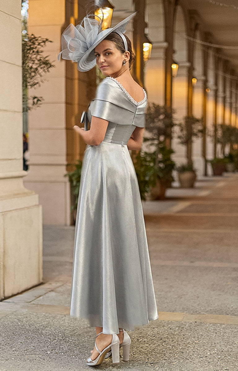 Woman Couture Club 2G16 - Silver Mika Occasion Dress with Contemporary Elegant Styling standing in an elegant outdoor setting with columns and plants.