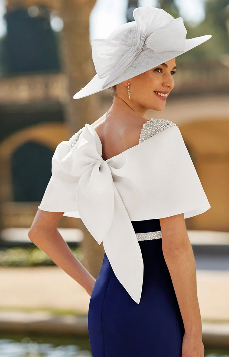 Rosa Clara 8G53 Outfit available at All About Mum Mother of the Bride or Groom Boutique. Photo shows a Woman wearing a white hat with a large bow and a blue dress, standing outdoors.