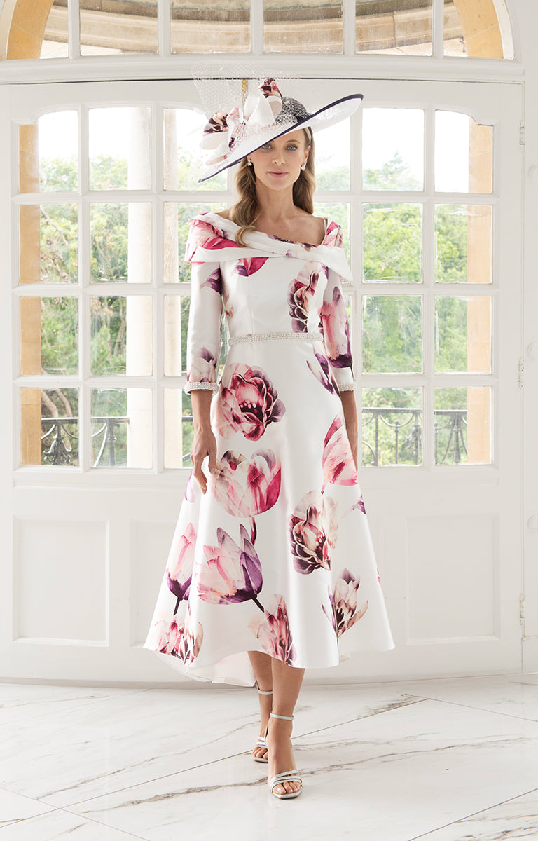 Woman wearing Irresistible IR8807G - Pink and Fuchsia A-Line Midi Dress with Asymmetric Neckline in a bright room with large windows.