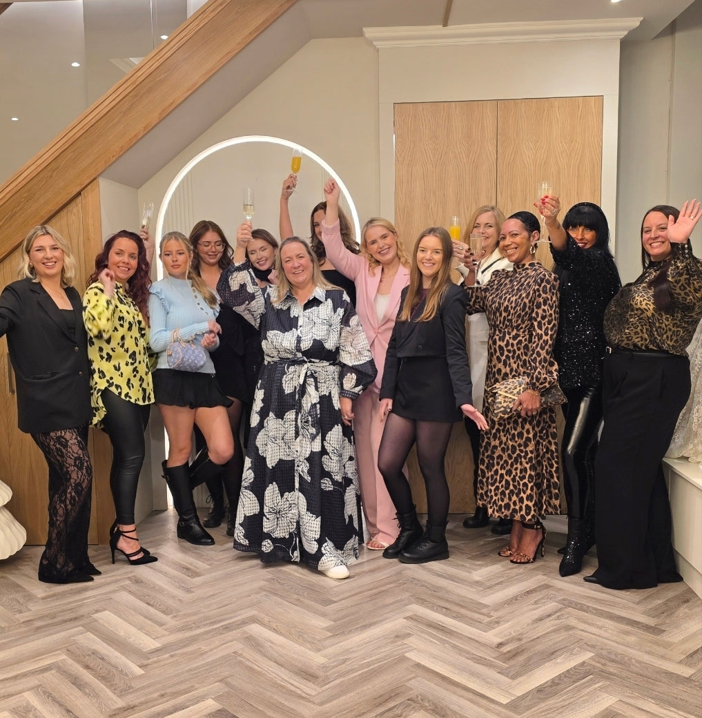 Photo of the team from All About Eve Bridalwear and All About Mum (Mother of the Bride or Groom Occasion wear Boutique and online retailer) posing together in a room with wooden staircase and modern decor.
