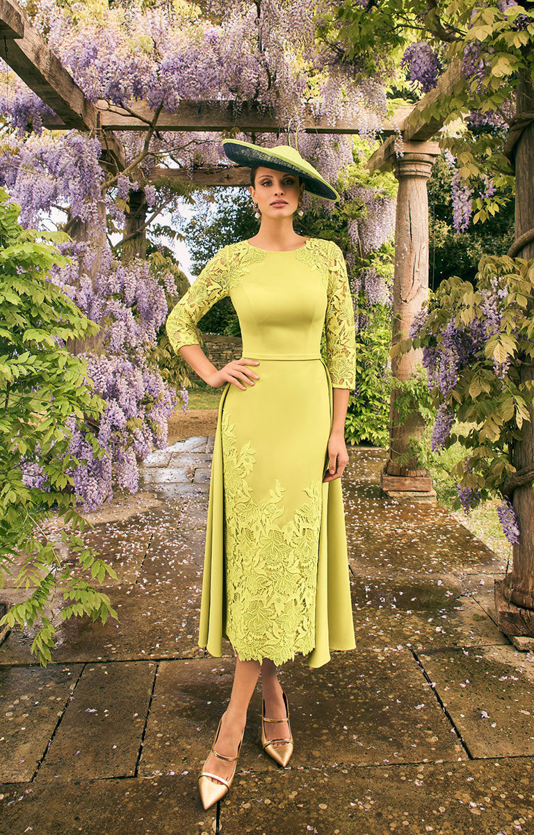 Woman wearing Veni Infantino 992772 - Lime Full-Length Crepe Dress with Lace Accents and Half Overskirt standing in a garden with wisteria