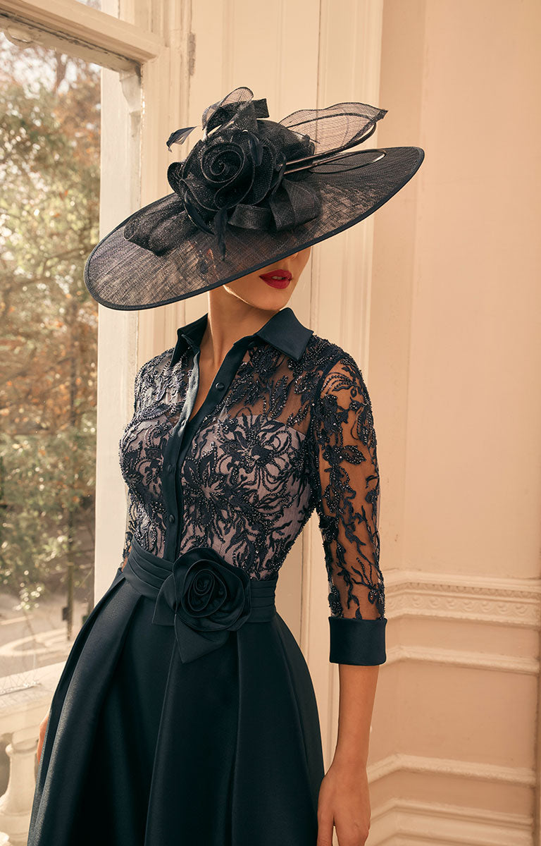 Woman wearing Veni Infantino 992805 - French Navy Occasion Dress with Silver Embroidery with a large decorative hat indoors.